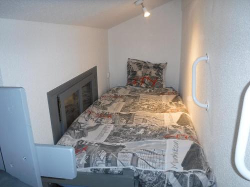 een kleine slaapkamer met een bed met een krant erop bij Studio Châtel, 1 pièce, 3 personnes - FR-1-200-316 in Châtel
