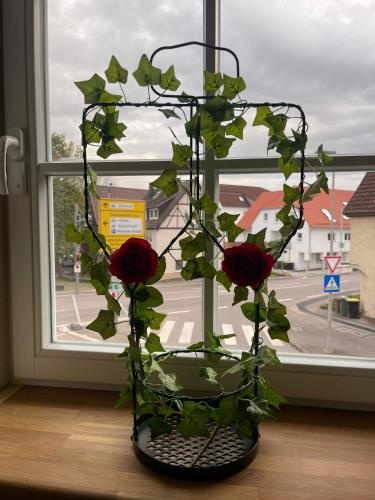 a vase filled with roses in front of a window at Rose Boardinghouse 24h-7d Self Check-In Automat in Großbottwar