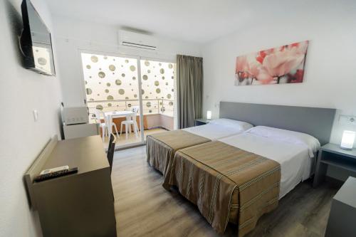 a hotel room with a bed and a desk and a television at Hostal Anna Benidorm in Benidorm