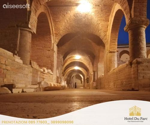 an empty hallway in a building with columns and ceilings at Hotel Du Parc in Atri
