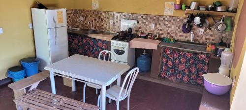 a small kitchen with a table and a refrigerator at Do Alto da Montanha Pousada in Vale do Capao