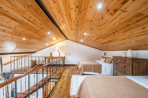 a room with two beds and a wooden ceiling at Ivy Cottage by Madeira Sun Travel in Faial