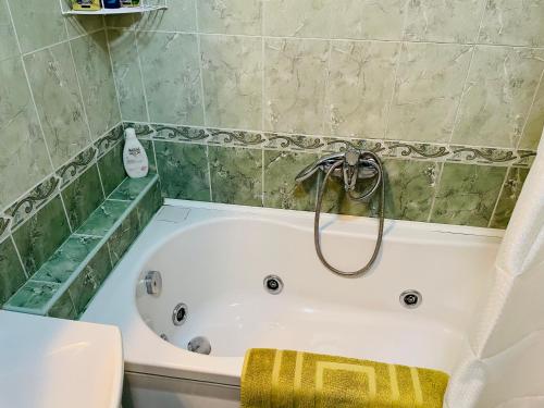 a bath tub in a bathroom with green tiles at Jolly Apartment - Belgrade in Belgrade