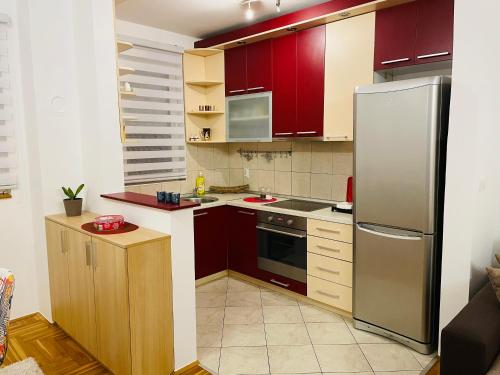 a kitchen with red cabinets and a stainless steel refrigerator at Jolly Apartment - Belgrade in Belgrade
