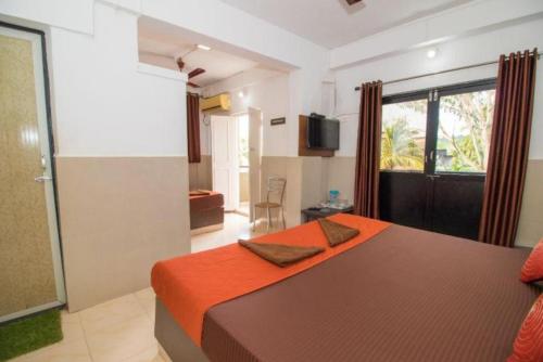 a bedroom with a large bed with an orange blanket at GRG Traveller in Panaji