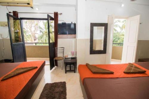 a room with two beds and a table and a mirror at GRG Traveller in Panaji
