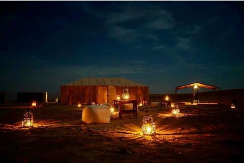 a tent in a field at night with lights at Peace of mind camp in Mhamid