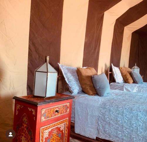 a bedroom with two beds and a table with a lamp at Peace of mind camp in Mhamid