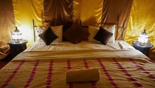 a bedroom with a large bed with two lamps at Peace of mind camp in Mhamid