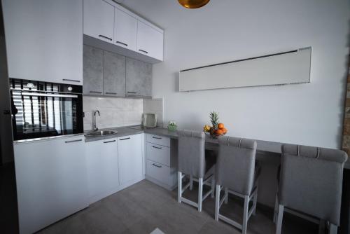 a kitchen with white cabinets and a counter with chairs at NLux 10 Apartment in Kopaonik
