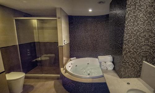 a bathroom with a tub and a toilet and a shower at Amérian Puerto Rosario Hotel in Rosario