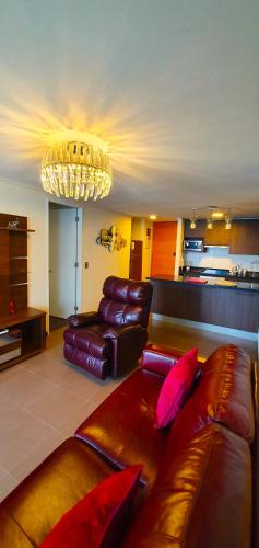 a living room with a leather couch and a chandelier at La mejor vista de la playa en Iquique in Iquique