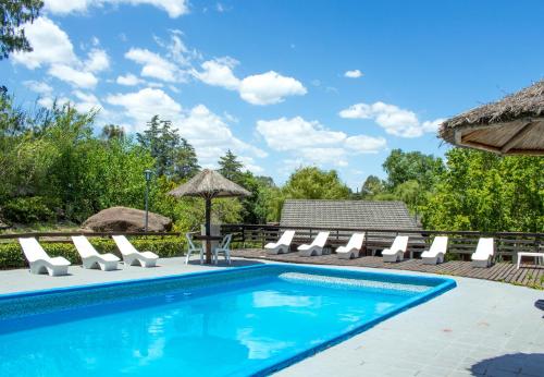 una piscina con tumbonas y sombrilla en Capri Hotel y Cabañas by CPH en Villa Carlos Paz