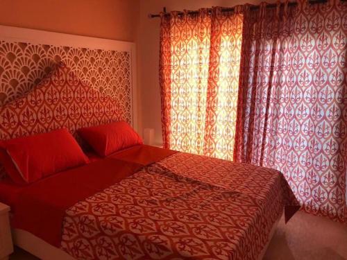 a bedroom with a red bed with red pillows and curtains at Bright Get Away Condo in Sharm El Sheikh