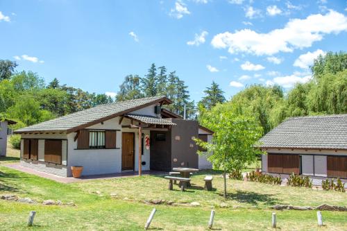 una pequeña casa con un banco delante en Capri Hotel y Cabañas by CPH en Villa Carlos Paz