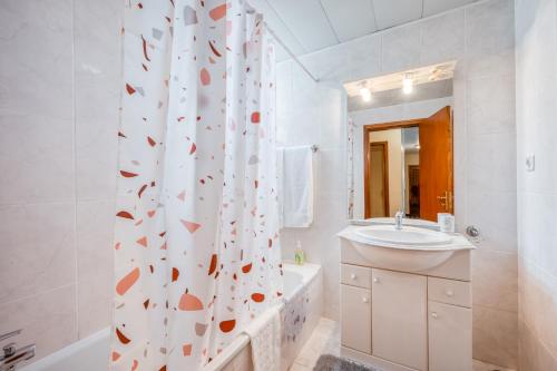 a bathroom with a tub and a sink and a shower curtain at Apartamento Vista Azul in Funchal