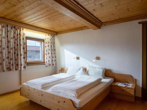 a large bed in a room with a wooden ceiling at Kröpflhof in Sankt Johann in Tirol