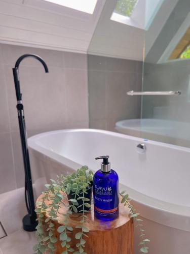 a blue bottle of soap on a table next to a bath tub at Amalú Luxury View Cabins in Monteverde Costa Rica
