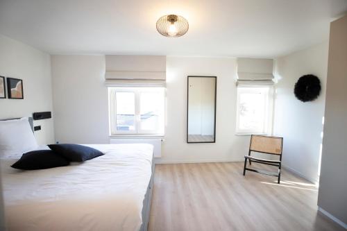 a white bedroom with a bed and a chair at Vakantiewoningen Liefst in Epen in Epen