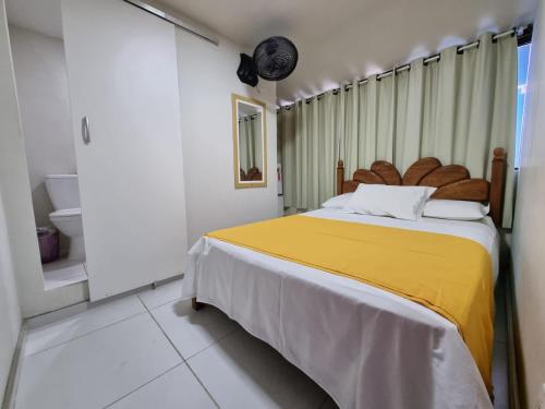 a bedroom with a large bed with a yellow blanket at Casa Da Praia in Cabo Frio