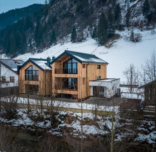 uma casa de madeira no meio de uma montanha de neve em Haus Alpenfan em Grossarl