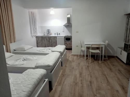 a room with three beds and a table and a kitchen at Room Click inn in Gjirokastër