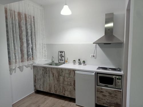 a white kitchen with a sink and a microwave at Room Click inn in Gjirokastër