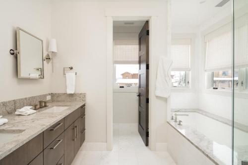 Un baño con dos lavabos, una bañera y un espejo. en Spanish Peaks - Highlands Cabin 19, en Big Sky