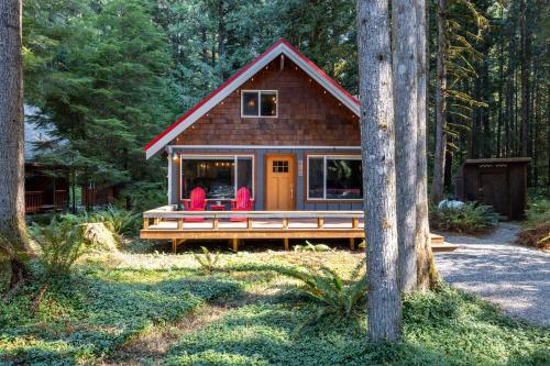 a small cabin in the woods with two red chairs at On Mountain Time in Glacier
