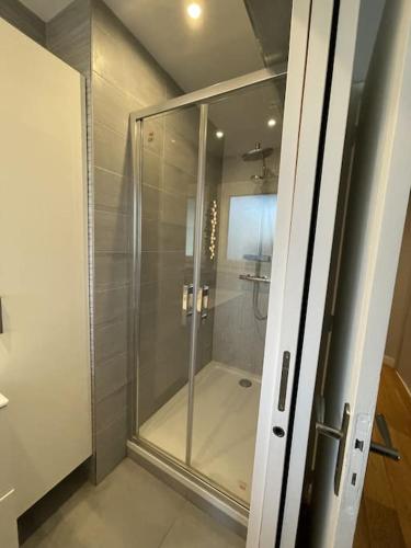 une douche dans une salle de bain avec une porte vitrée dans l'établissement Appartement Roland-Gaross/Boulogne-Billancourt, à Boulogne-Billancourt