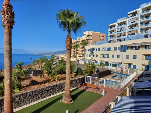 a view of a resort with palm trees and a swimming pool at Duplex with sea views, garden and terrace in Santa Cruz de Tenerife