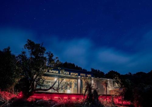 a house lit up at night with red lights at Tokoeka PurePod in Stewart Island