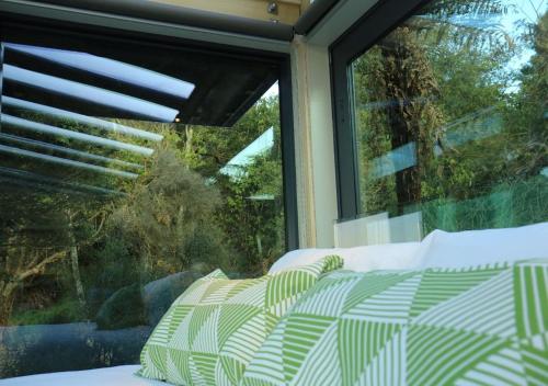 a bed in front of a window with a view at Tokoeka PurePod in Stewart Island