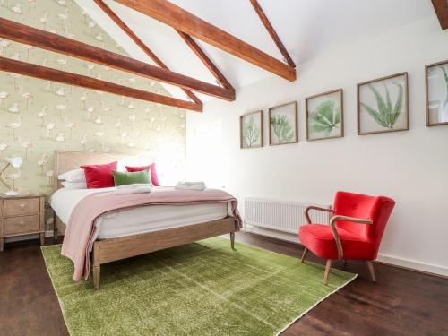 a bedroom with a bed and a red chair at The Old Smokehouse in St Austell
