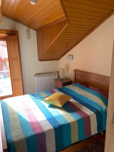 a bedroom with a bed with a striped comforter at Recantos da Estrela in Sabugueiro