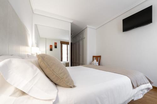 a white bedroom with a large white bed with pillows at Dolce Vita Centro in Vitoria-Gasteiz