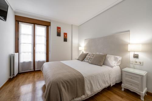a white bedroom with a large bed and a window at Dolce Vita Centro in Vitoria-Gasteiz