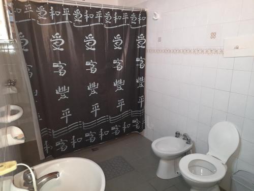 baño con aseo y cortina de ducha con escritura asiática en Complejo El Tata en Potrerillos