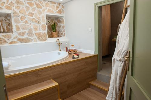 La salle de bains est pourvue d'une baignoire et d'un mur en pierre. dans l'établissement locanta, à Ioannina