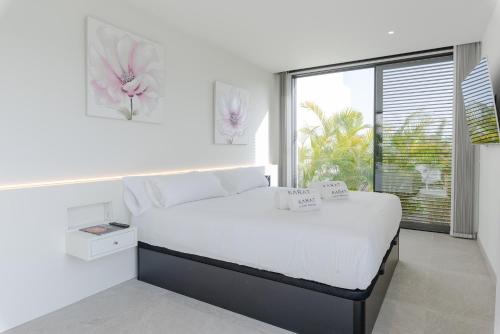 a white bedroom with a bed and a window at Karat Villa Macaronesia in Adeje