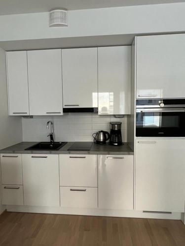una cocina blanca con armarios blancos y fregadero en City apartment nearby Airport en Vantaa