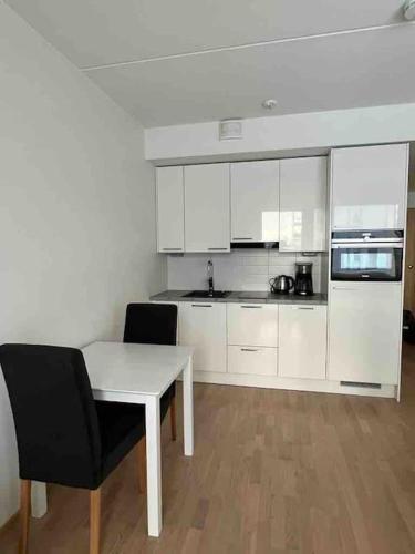 a kitchen with white cabinets and a table and chairs at City apartment nearby Airport in Vantaa