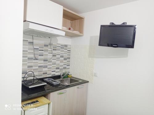 a kitchen with a sink and a tv on the wall at Il Bungalow di Villa Mirko in Vaccarizzo - Delfino