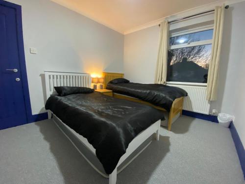 a bedroom with two beds and a window at Harewood Lodge - Single and Double Rooms Self Serve Apartment in King's Lynn
