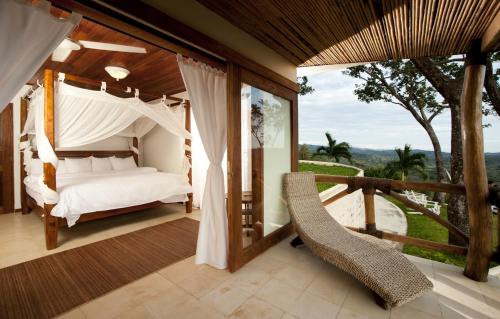 a bedroom with a bed and a balcony with a view at Tierra Magnifica Boutique Hotel in Nosara
