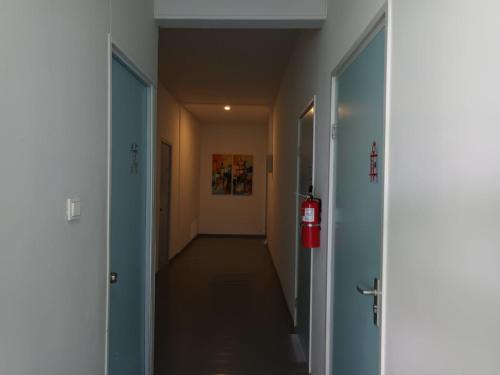 a long hallway with two doors and a fire extinguisher at Twenty4 Hostel in Paramaribo