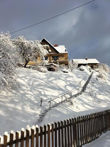 a snow covered yard with a house and a fence at Agroturystyka Na Kępie in Wisła