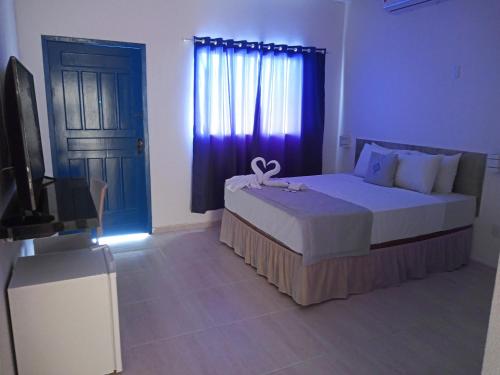 a bedroom with a bed and a television and a door at La Suite Praia Hotel in Caucaia