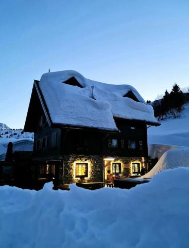 a house covered in snow with lights on at Zoncolan Laugiane 1616 Natura Cucina e Relax sul Monte Zoncolan in Sùtrio