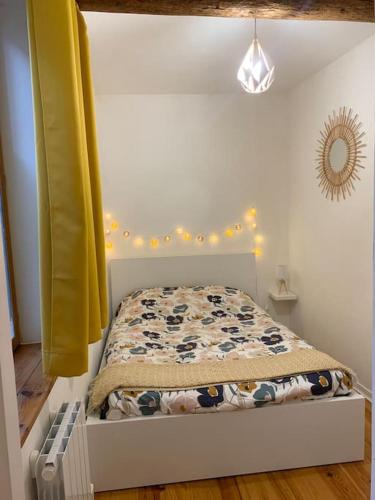 - une petite chambre avec un lit et un rideau jaune dans l'établissement Le petit cocon Nîmois, à Nîmes